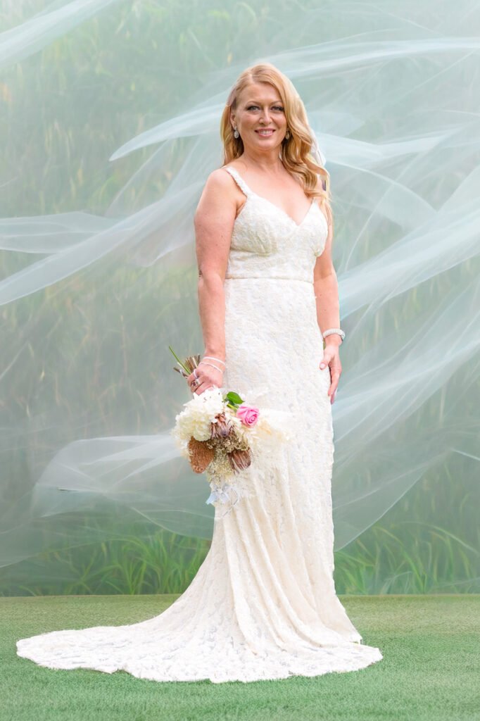 Bride with Lace Swirling in Wind against Green Hill