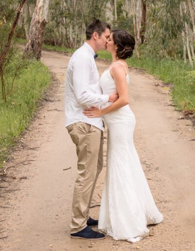 Wedding Couple Kissing on Road that enters a Forest