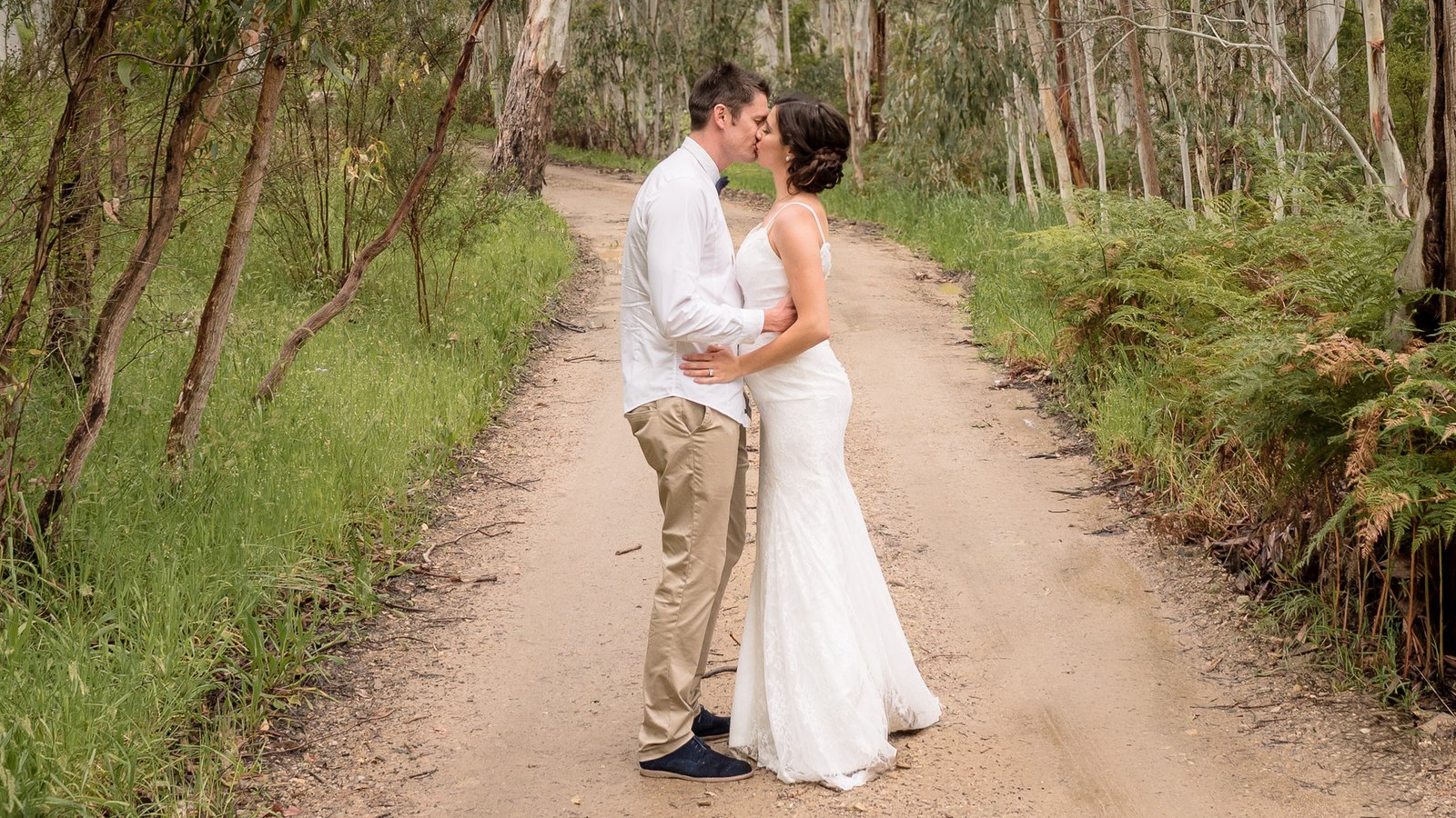 Wedding Couple Kissing on Road that enters a Forest